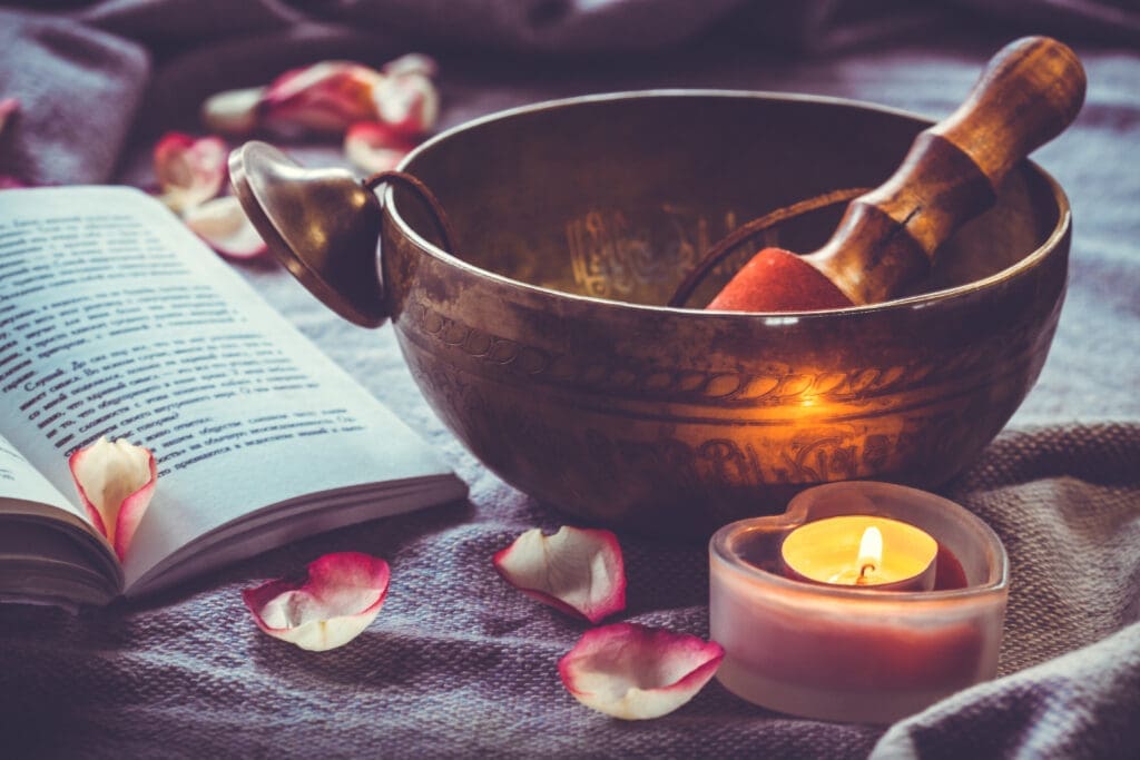 Tibetan singing bowl with book candle and rose petal herbs